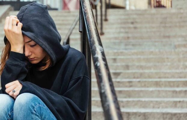 Depressed young woman sitting on the street Yesil Science Depressed young woman sitting on the street